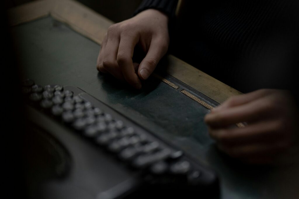 Close-up of hands near an old-fashioned typewriter on a wooden desk creating a nostalgic atmosphere.
