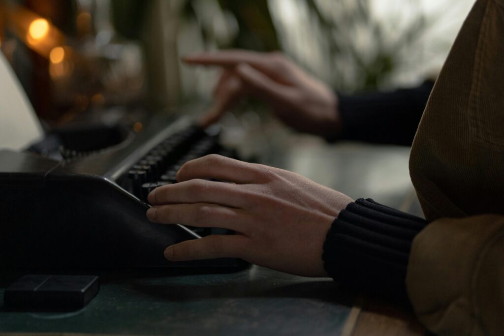 Moody, close-up image of hands typing on an old-fashioned typewriter indoors.